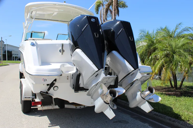 Slide: The Image of 2018 Boston Whaler 270 Vantage boat with dual outboard engines, parked near palm trees. - 10