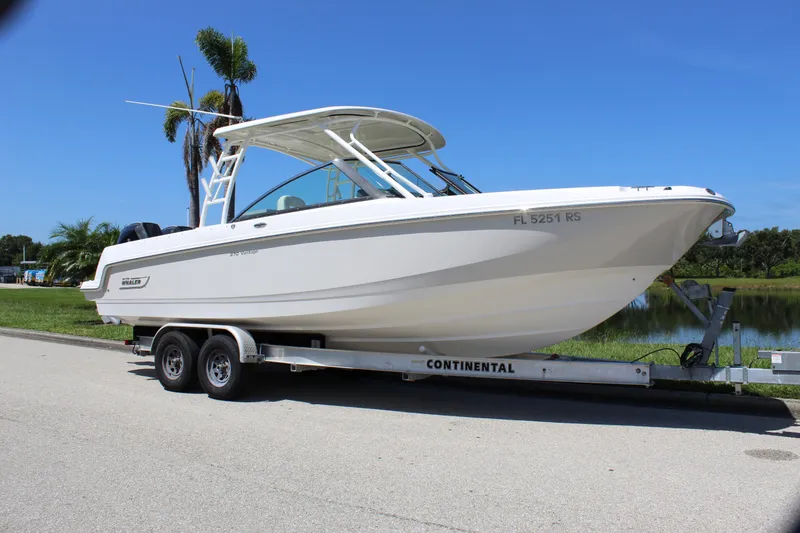 Slide: The Image of 2018 Boston Whaler 270 Vantage boat on trailer, parked near a lake. - 15