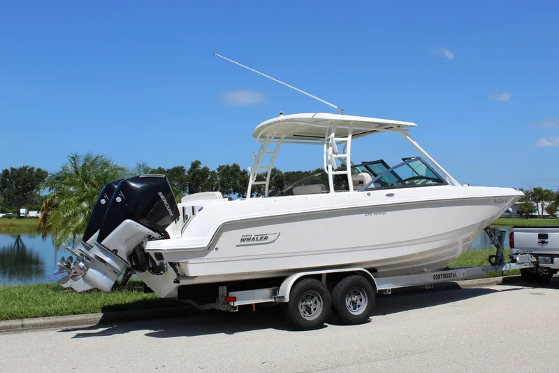 Slide: The Image of 2018 Boston Whaler 270 Vantage boat on trailer, parked near a lake under clear blue sky. - 18