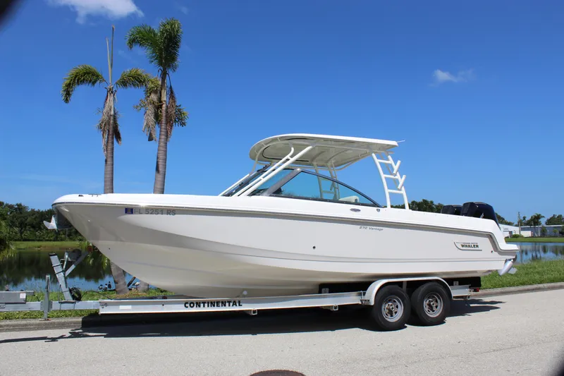 Slide: The Image of 2018 Boston Whaler 270 Vantage boat on trailer, parked near palm trees and water. - 3