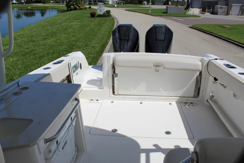 Slide: The Image of 2018 Boston Whaler 270 Vantage boat interior with dual engines, docked near a grassy area. - 37