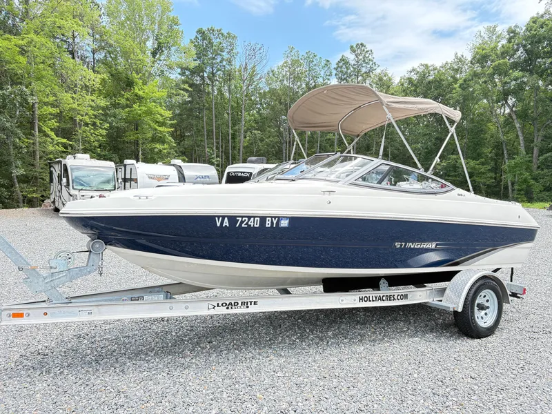 The Image of 2016 Stingray 188 LX boat on trailer, parked outdoors with trees in the background. - 1