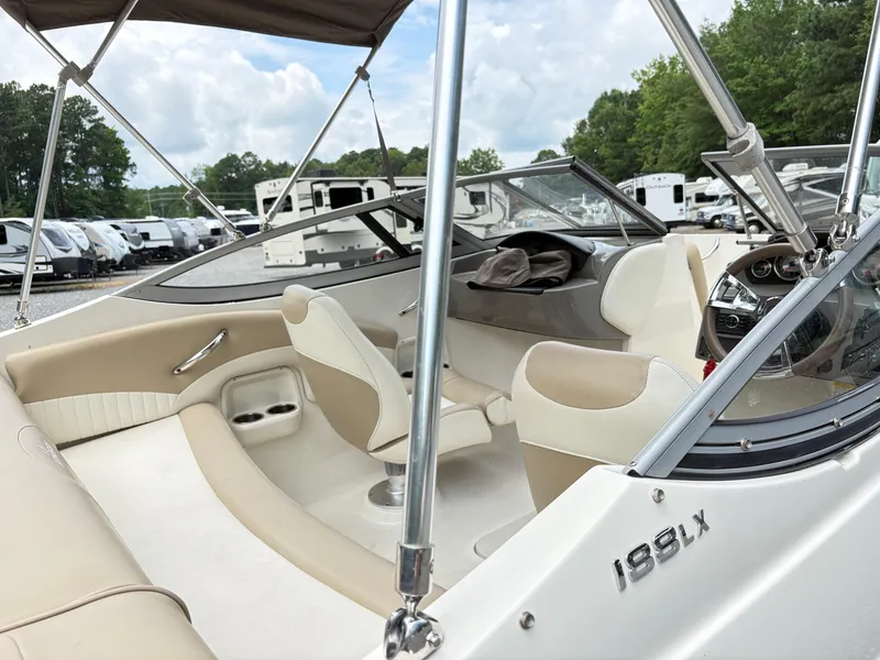 Slide: The Image of 2016 Stingray 188 LX boat interior with beige seating and dashboard, parked near RVs. - 7