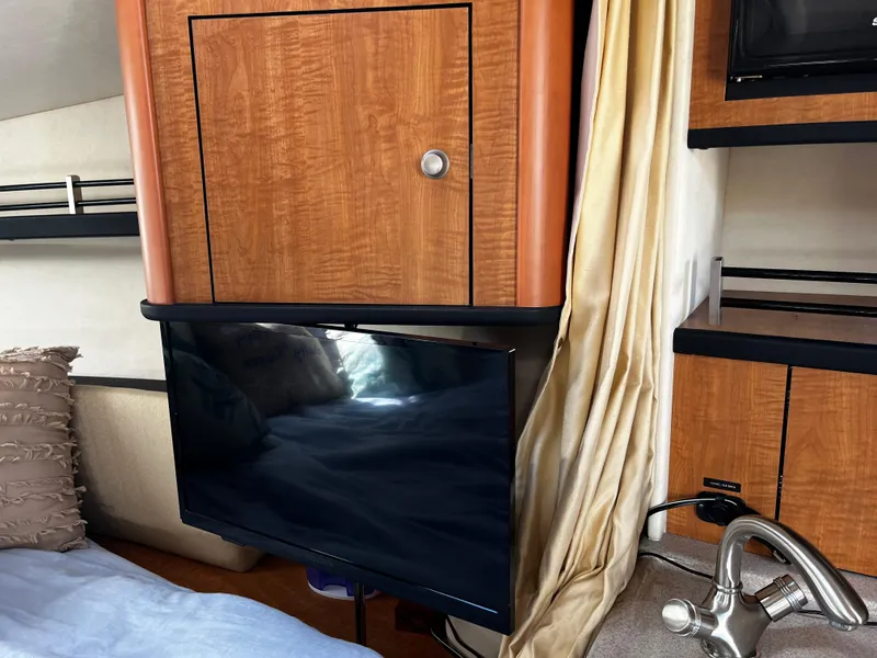 Slide: The Image of Interior of 2006 Sea Ray 290 Sundancer with TV, wooden cabinetry, and modern faucet. - 19