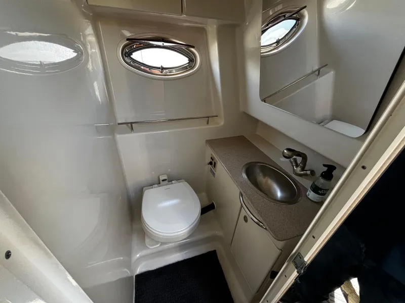 Slide: The Image of 2006 Sea Ray 290 Sundancer bathroom with toilet, sink, and porthole window. - 24