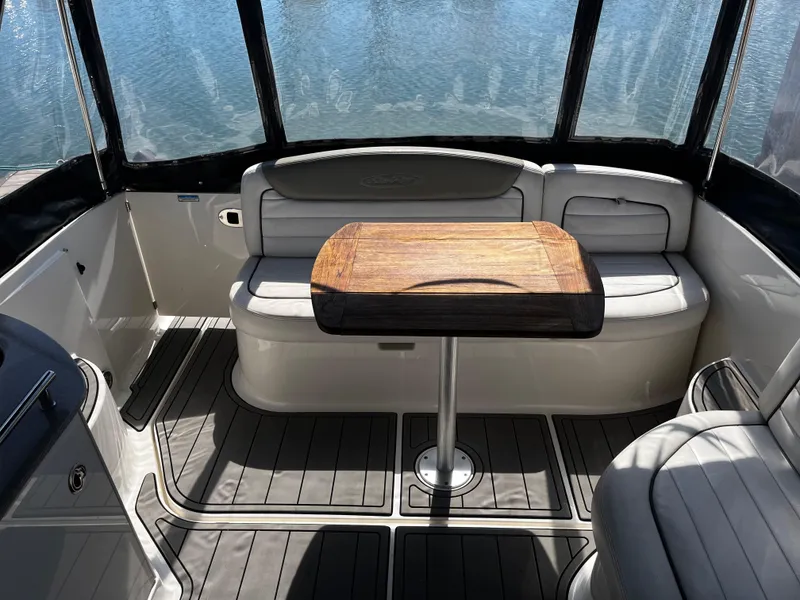 Slide: The Image of 2006 Sea Ray 290 Sundancer interior with seating and wooden table, overlooking water. - 27