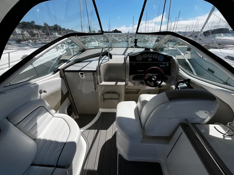 Slide: The Image of 2006 Sea Ray 290 Sundancer cockpit with modern controls and seating, docked at marina. - 8
