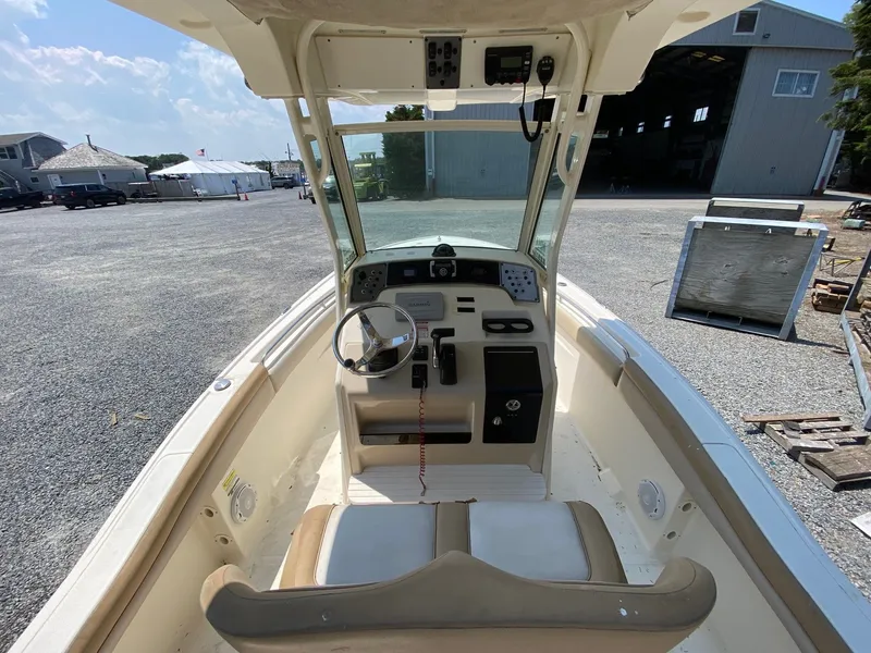 Slide: The Image of 2012 Scout 225 XSF boat interior with steering wheel and dashboard, parked outdoors. - 8