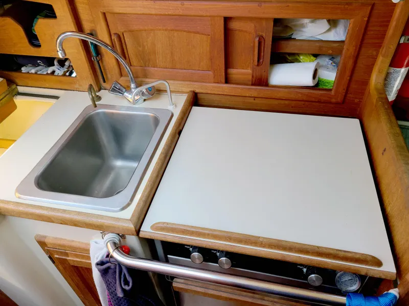 Slide: The Image of Compact kitchen area in a 1987 Pacific Seacraft Dana 24 sailboat, featuring a sink and stove. - 10