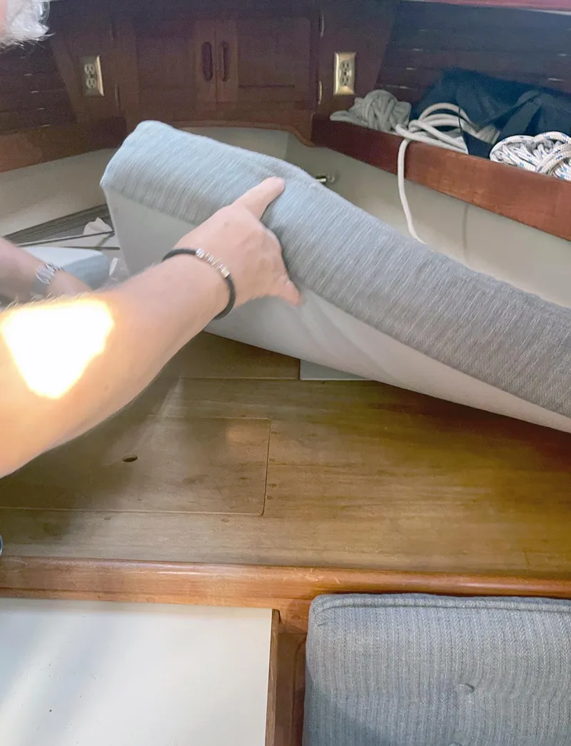 Slide: The Image of Person adjusting cushion on 1987 Pacific Seacraft Dana 24 sailboat interior. - 13