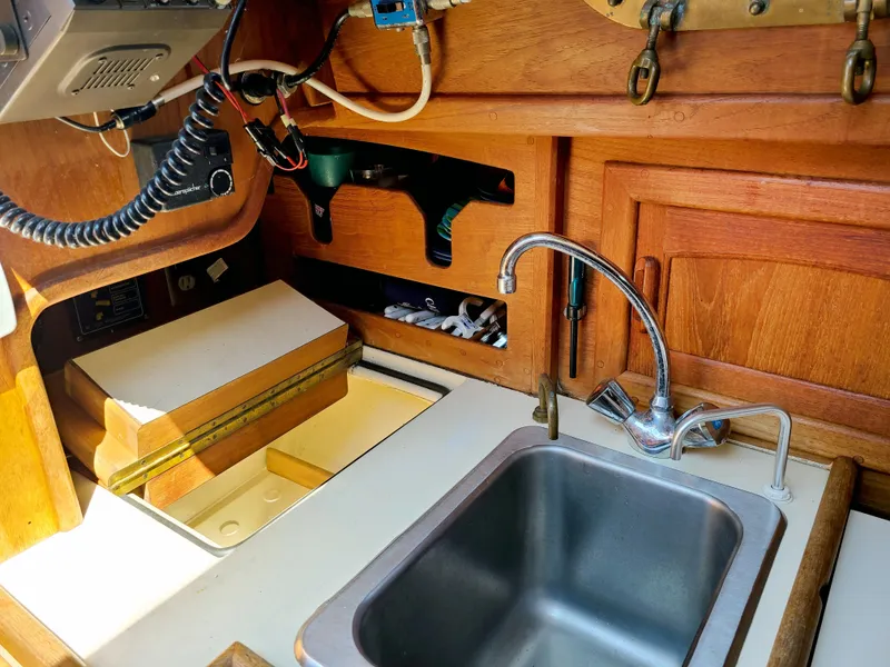 Slide: The Image of 1987 Pacific Seacraft Dana 24 yacht galley with sink and wooden cabinetry. - 9