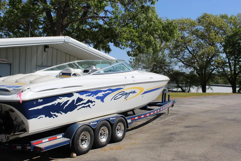 Slide: The Image of 2002 Baja 342 speedboat on trailer, parked near a lake with trees in the background. - 10