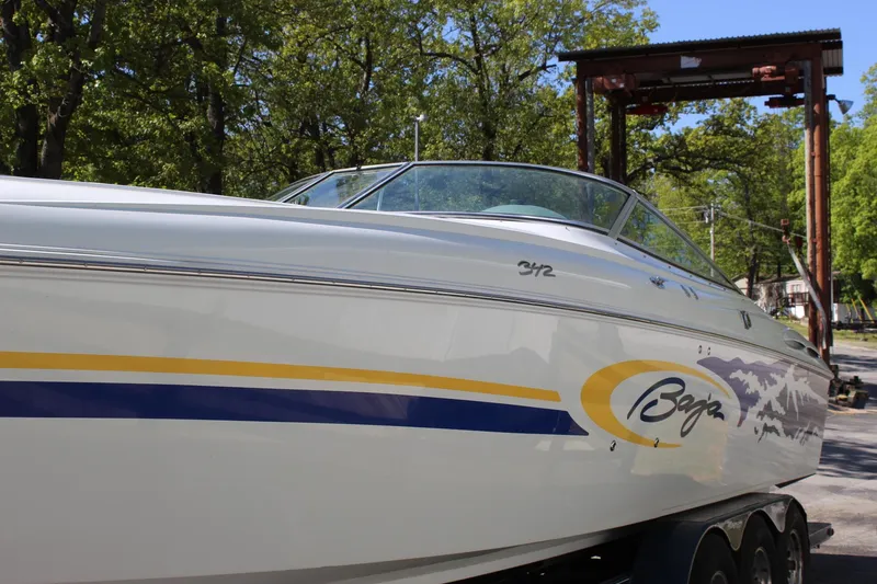 Slide: The Image of 2002 Baja 342 speedboat with vibrant graphics, parked outdoors under trees. - 15