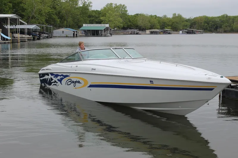 Slide: The Image of 2002 Baja 342 boat on a calm lake with docks and trees in the background. - 6