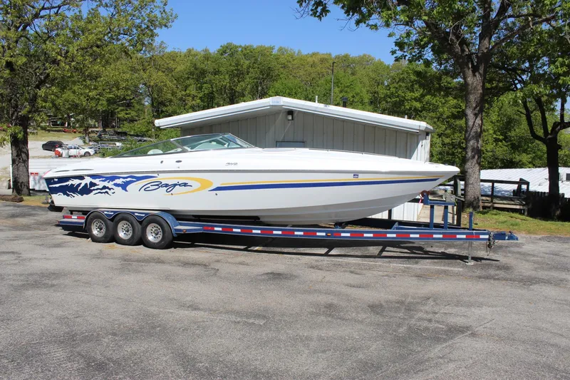 Slide: The Image of 2002 Baja 342 boat on trailer, parked outdoors near trees and a building. - 8
