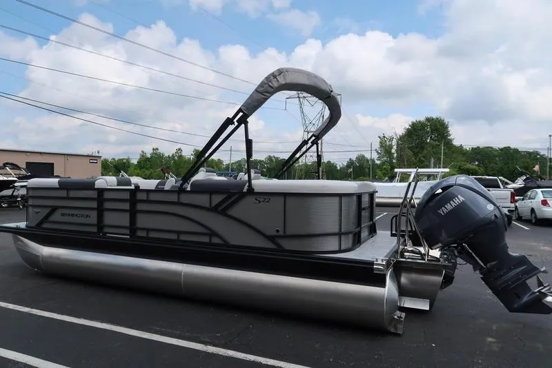 Slide: The Image of 2026 Bennington S Quad Bench 22 SSR pontoon boat with Yamaha outboard motor, parked outdoors. - 12