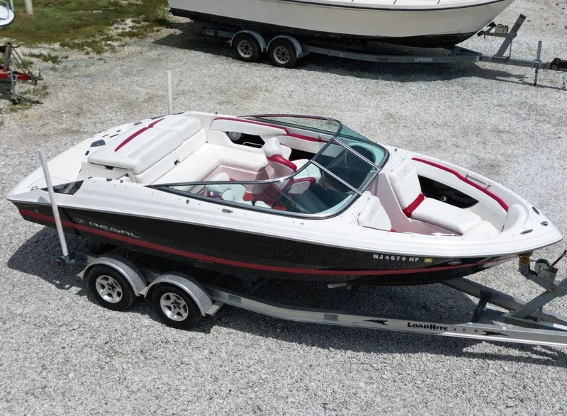 Slide: The Image of 2009 Regal 2200 Bowrider boat on trailer, white and red interior, parked on gravel. - 8