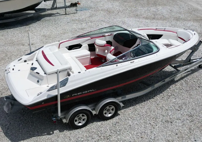 Slide: The Image of 2009 Regal 2200 Bowrider boat on trailer, white and red interior, parked on gravel. - 9