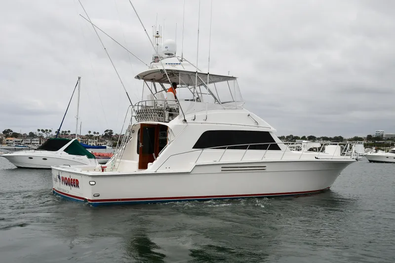 Slide: The Image of 1988 Bertram 54 Convertible yacht on water, overcast sky, marina background. - 0