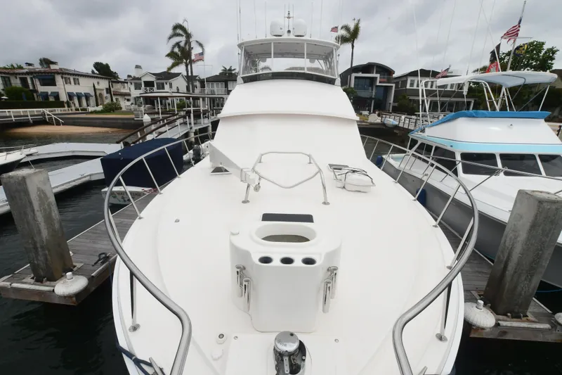 Slide: The Image of 1988 Bertram 54 Convertible yacht docked at marina, surrounded by other boats and waterfront homes. - 2