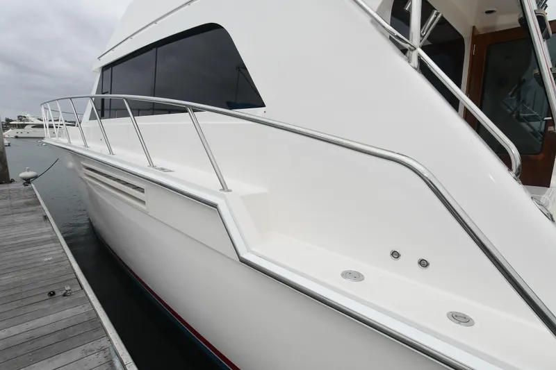 Slide: The Image of 1988 Bertram 54 Convertible yacht docked, showcasing sleek white exterior and stainless steel railings. - 3