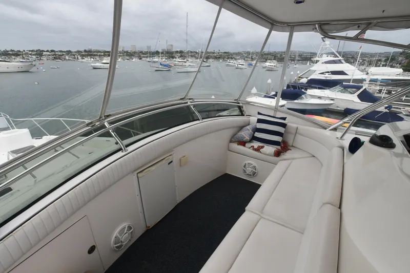 Slide: The Image of 1988 Bertram 54 Convertible yacht interior with marina view, featuring white seating and nautical decor. - 5