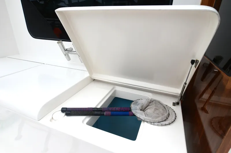Slide: The Image of Open storage compartment on 1988 Bertram 54 Convertible boat with fishing net and rod. - 9