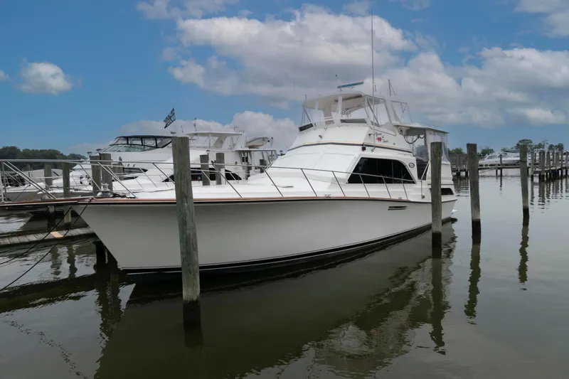 Slide: The Image of 1985 Ocean Yachts 46 Sunliner docked at marina under blue sky. - 2