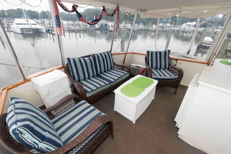 Slide: The Image of 1985 Ocean Yachts 46 Sunliner interior with striped seating, wicker furniture, and marina view. - 4