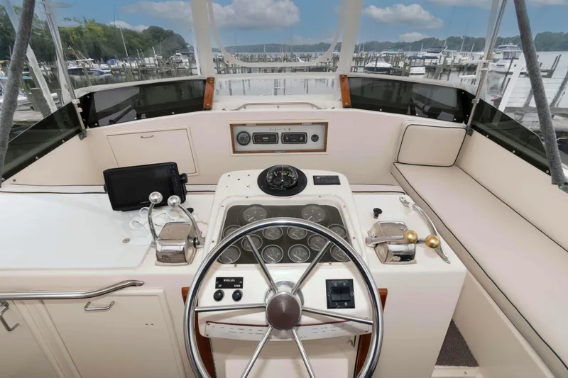 Slide: The Image of 1985 Ocean Yachts 46 Sunliner helm with steering wheel, gauges, and marina view. - 6