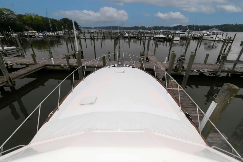 Slide: The Image of 1985 Ocean Yachts 46 Sunliner docked at a marina under a cloudy sky. - 8