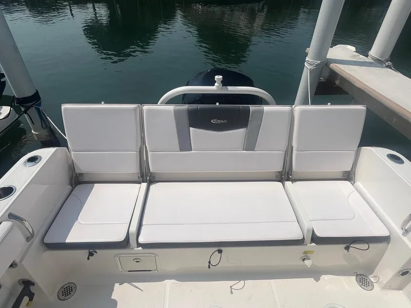 Slide: The Image of 2020 Robalo R230 Center Console boat seating area with white cushions and cup holders. - 10