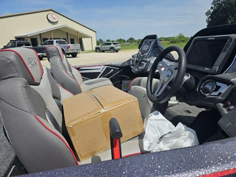 Slide: The Image of 2017 Skeeter FX21 LE boat interior with cardboard box on seat, near dealership building. - 7