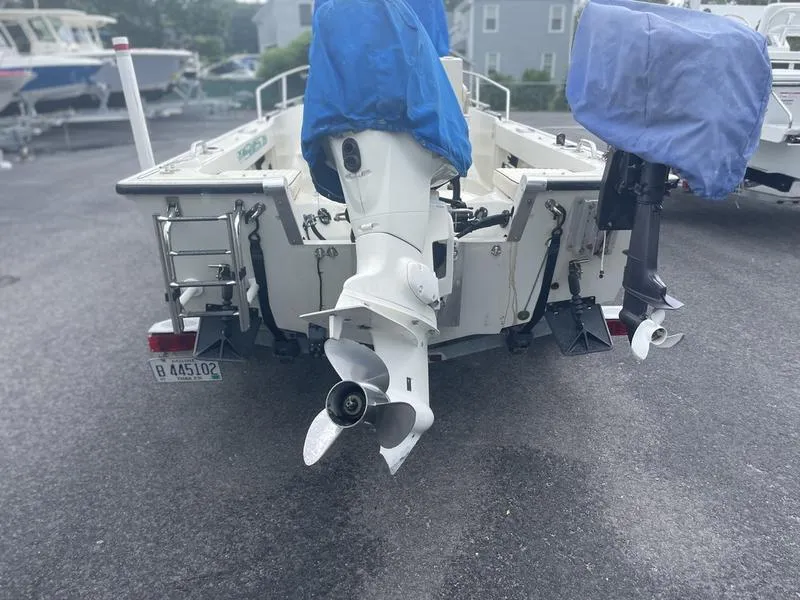 Slide: The Image of 1991 Boston Whaler 17 Outrage boat with dual outboard motors, covered and parked on asphalt. - 5