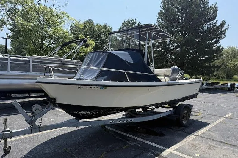 Slide: The Image of 1996 Parker 18 CC boat on trailer, parked outdoors with trees in the background. - 2