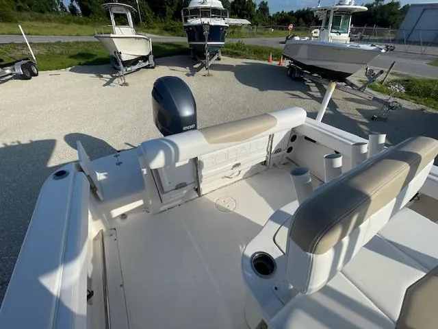 Slide: The Image of 2016 Robalo 2220 Center Console boat interior with seating and motor, parked outdoors. - 4