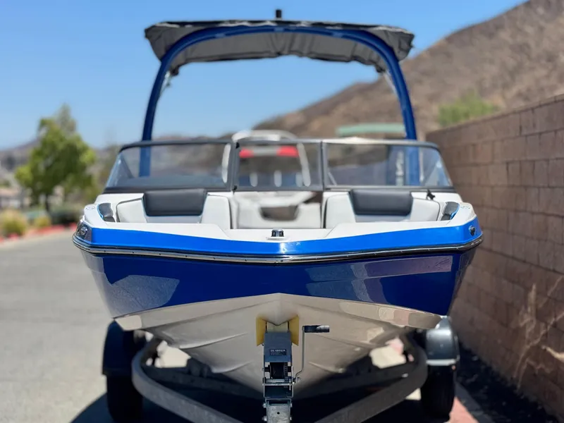 Slide: The Image of 2020 Yamaha AR195 boat on trailer, blue and white, parked outdoors. - 2