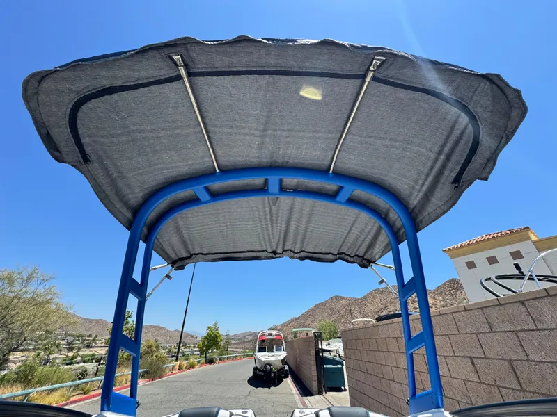 Slide: The Image of 2020 Yamaha AR195 boat with blue canopy, parked near mountains under clear sky. - 9