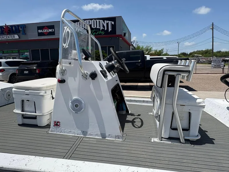 Slide: The Image of Center console boat with seating and coolers, parked outside a dealership under a clear sky. - 8