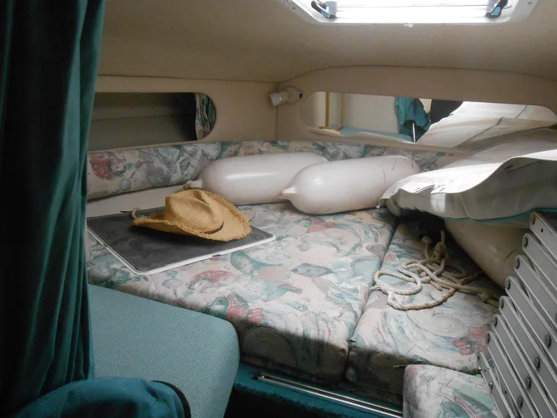 Slide: The Image of 1996 Sea Ray 290 Sundancer cabin interior with bed, hat, and boating accessories. - 19