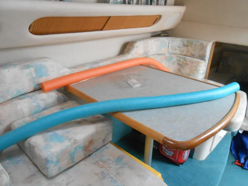 Slide: The Image of Interior of 1996 Sea Ray 290 Sundancer with table, seating, and pool noodles. - 20