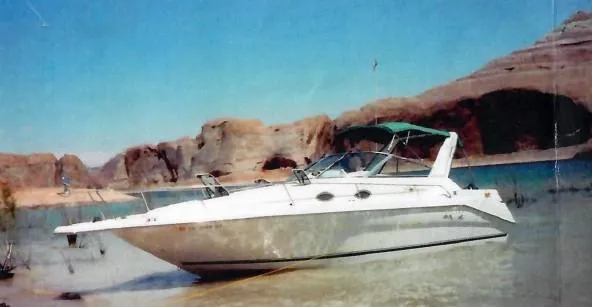 Slide: The Image of 1996 Sea Ray 290 Sundancer boat on calm water with rocky cliffs in the background. - 28