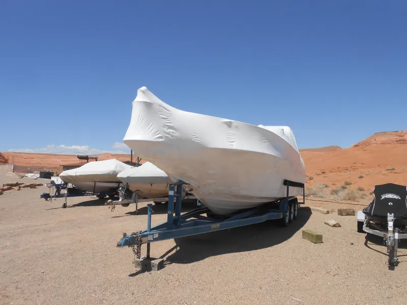 Slide: The Image of 1996 Sea Ray 290 Sundancer boat covered on trailer in desert landscape. - 4
