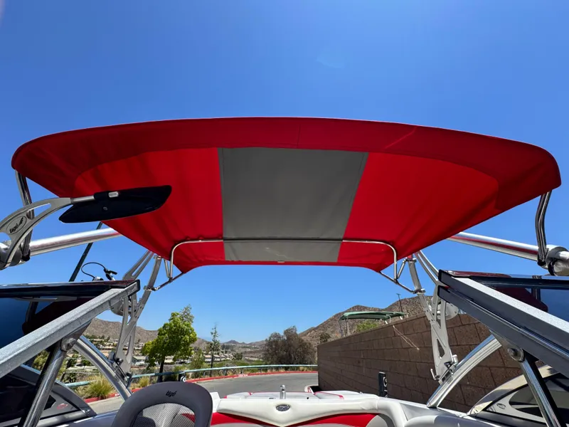 Slide: The Image of 2008 Tigé RZ2 boat with red and gray canopy under clear blue sky. - 11