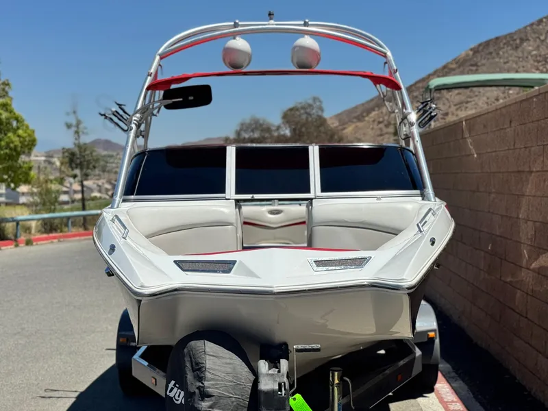 Slide: The Image of 2008 Tigé RZ2 boat on trailer, parked near a wall, sunny day. - 2