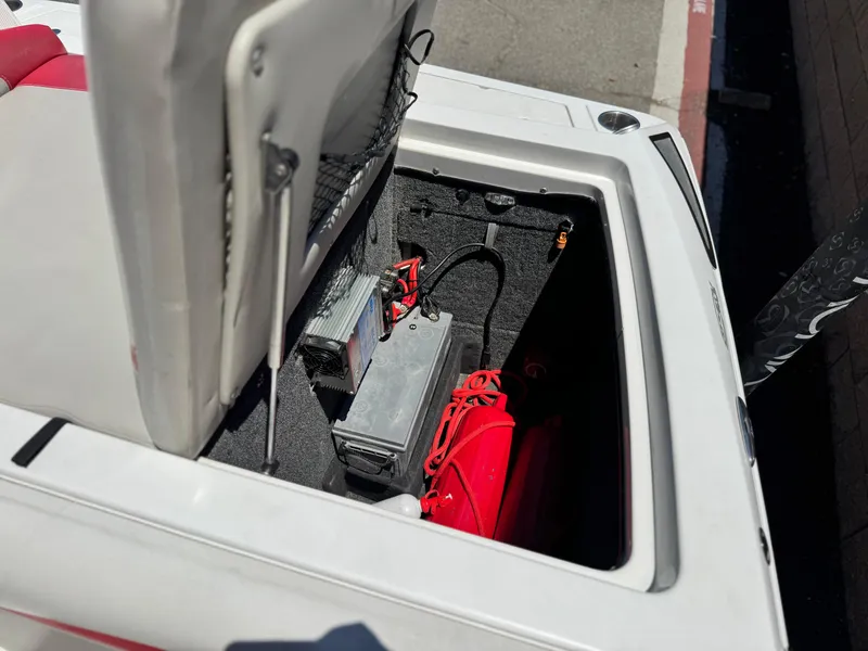 Slide: The Image of Open storage compartment in a 2008 Tigé RZ2 boat, showing battery and equipment. - 24