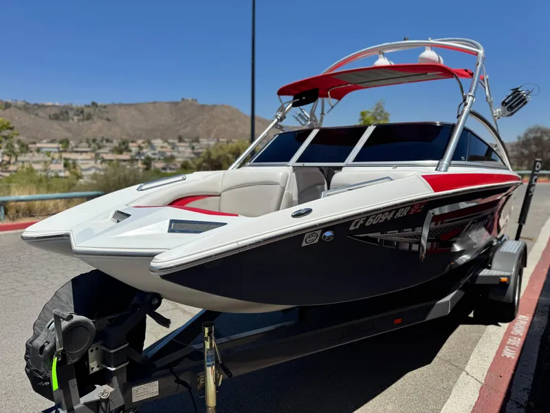 Slide: The Image of 2008 Tigé RZ2 boat on trailer, red and white design, parked on roadside. - 3