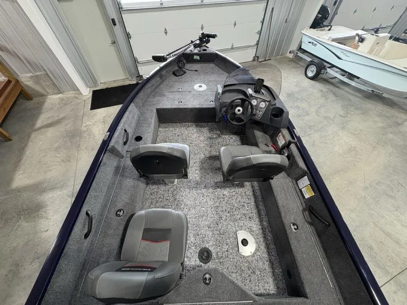 Slide: The Image of 2026 Tracker Pro Guide™ V-16 SC boat interior with seating and steering console in a garage. - 17