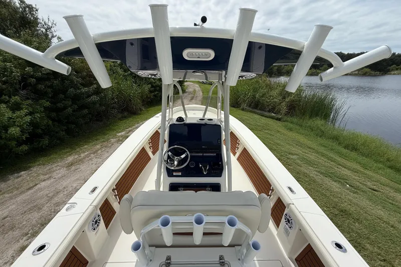 Slide: The Image of 2026 Pathfinder 2700 Open boat with rod holders, steering console, and scenic lake view. - 13