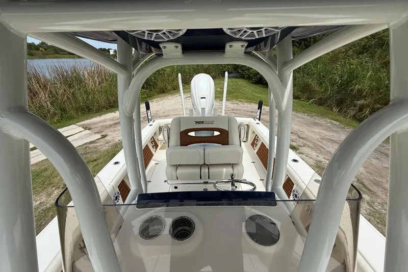 Slide: The Image of 2026 Pathfinder 2700 Open boat interior with seating and console, near a grassy shoreline. - 20